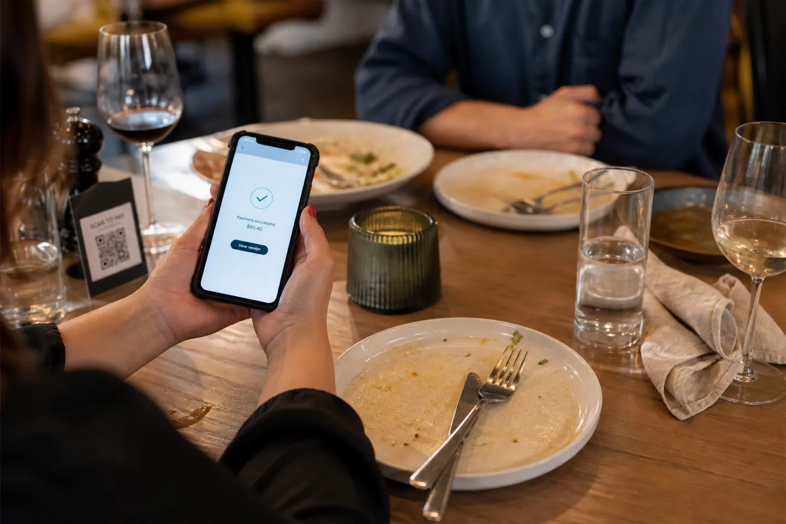 Gast bezahlt die Rechnung nach dem Essen am Tisch per Handy